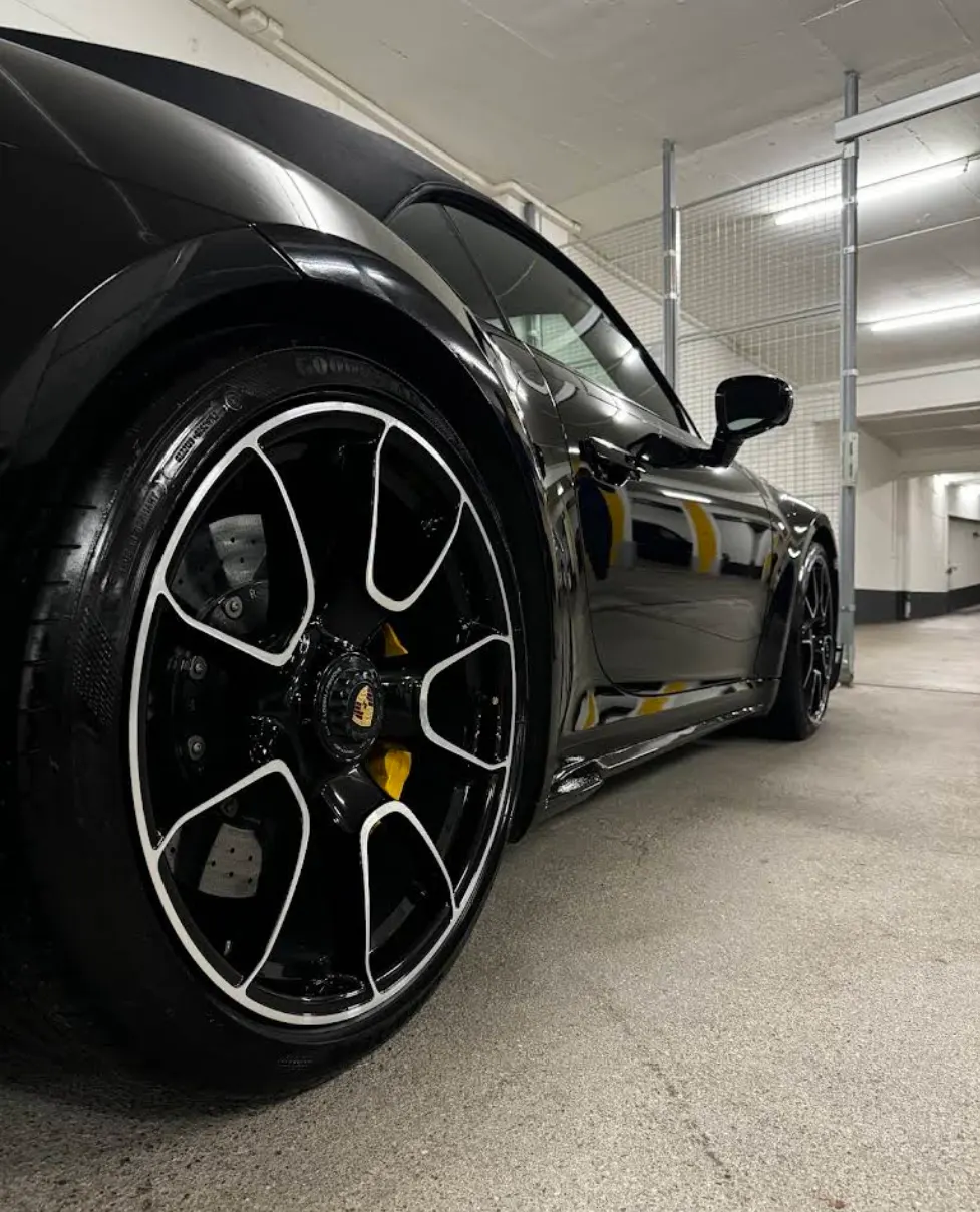 Schwarzer Porsche 911 Turbo mit glänzendem Lack und aufbereiteten Felgen in der Tiefgarage